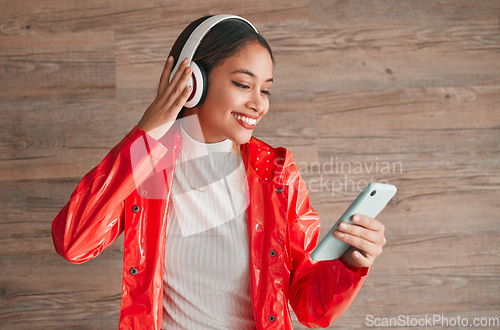 Image of Phone, headphones and happy woman with music isolated on wood background, audio streaming and mobile app. Gen z student or biracial person listening on cellphone, electronics sound and technology