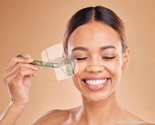 Image of Happy woman, beauty or face massage with roller, facial product for healthy skincare on studio background. Smile, crystal stone treatment or girl model with dermatology cosmetics or jade marketing