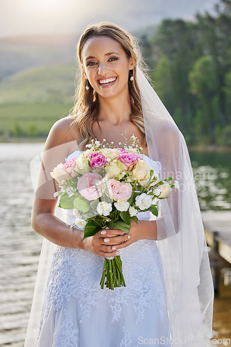 Image of Portrait, bride and smile with flower bouquet at lake, nature and celebration of commitment, love and marriage. Happy woman, wedding and flowers outdoor for bridal fashion, style and excited ceremony