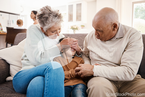 Image of Happy, playful and child with grandparents on sofa of family living room for bonding, affectionate and fun. Playing boy, hide and seek with senior people at home for happiness, generations and games