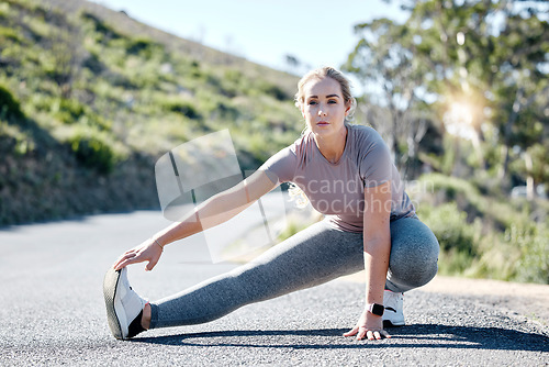 Image of Fitness, woman and stretching legs on road for exercise, start or workout in nature. Serious, determined and fit sporty female in warm up leg stretch getting ready for training or running outdoors