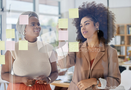 Image of Team, brainstorming and business people with glass board, writing ideas on sticky note with collaboration and strategy. Planning, meeting and women working together, female employees and partnership