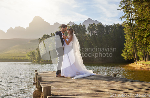 Image of Love, dance and a married couple on a pier over a lake in nature with a forest in the background after a ceremony. Wedding, romance or water with a bride and groom in celebration of marriage outdoor