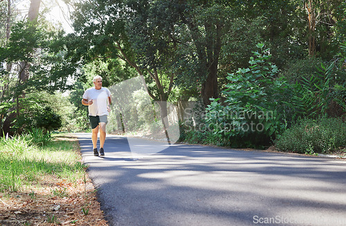 Image of Man, exercise and outdoor in nature for run, workout and training on road with trees for fitness. Happy senior male person smile and thinking of cardio health and wellness while running in retirement