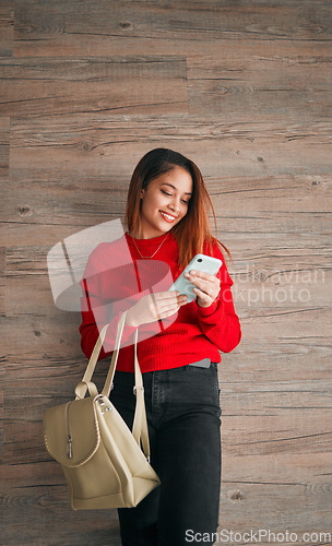 Image of Phone, fashion and a woman in studio on a wooden background typing a text message or reply. Mobile, contact and attractive young female browsing social media while carrying a handbag in red clothes