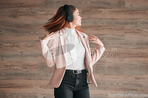 Image of Dancing, happy and woman listening to music with happiness or streaming audio online using headphones. Radio, wellness and excited female person dance isolated in a wooden wall background