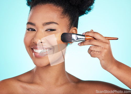 Image of Black woman, foundation and brush in studio for beauty with skin test, smile and cosmetics by blue background. Happy african model, girl and makeup for aesthetic, glow and skincare with concealer