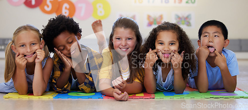 Image of Kids, floor and group portrait with funny face in school classroom, solidarity or diversity in childhood. Girl, boy and children in class, academy and happy multicultural friends, together or playful