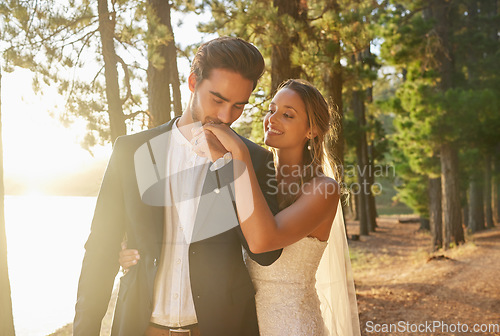 Image of Kiss, smile and couple at a nature wedding, celebration and marriage ceremony. Happy, affection and a man and woman kissing hand for loyalty, commitment and love at an event in a forest or woods