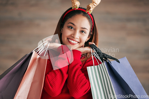 Image of Portrait, christmas headband and female with shopping bags for a festive or holiday celebration. Happy, smile and face of a woman model with gifts or presents with xmas reindeer ears for an event.