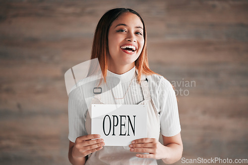 Image of Cafe, portrait and woman holding an open sign in studio on a blurred background. Coffee shop, small business startup and management with a young female entrepreneur indoor to display advertising