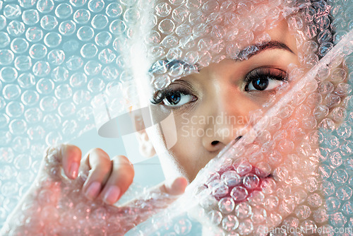 Image of Bubble wrap, cosmetics and face of woman with makeup, red lipstick and skincare products in studio. Creative art, beauty mockup and girl with facial glow, aesthetic and luxury style with plastic tear