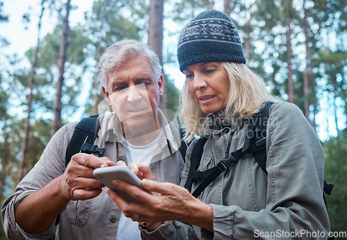 Image of Phone, hiking and mature couple of friends search for location, outdoor guide or wellness blog tips in forest. Senior people trekking or travel in woods on smartphone, cellphone or mobile app for map