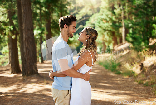 Image of Happy couple, hug and outdoor forest road of young people showing love for engagement announcement. Woods, trees and care of a woman and man together on holiday in nature with a smile and happiness