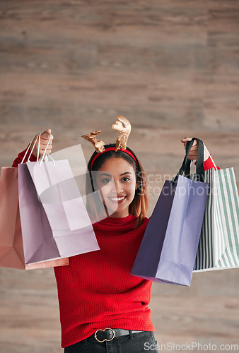 Image of Shopping bags, happy and female with a christmas headband for a festive or holiday celebration. Happiness, smile and portrait of a woman model with gifts or presents with xmas reindeer ears for event