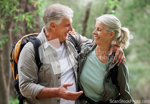 Image of Talking, hiking and happy senior couple on nature adventure in forest, woods and mountain for exercise. Fitness, retirement and elderly man and woman smile, in conversation and trekking for wellness