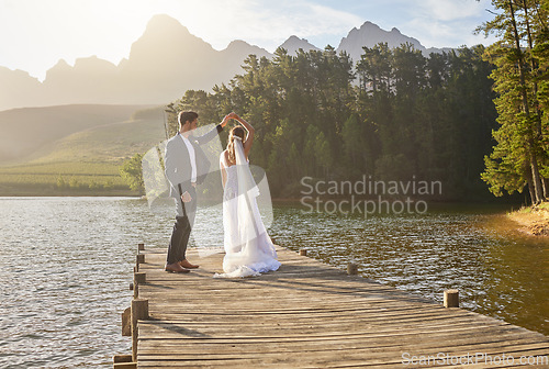 Image of Married, dance and a couple on a pier over a lake in nature with a forest in the background after a ceremony. Wedding, love or water with a bride and groom in celebration of their marriage outdoor