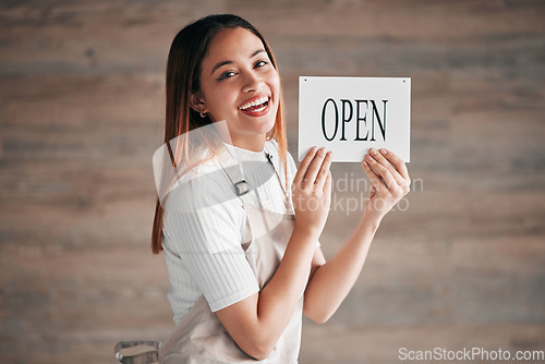 Image of Coffee shop, portrait and woman holding an open sign in studio on a blurred background for hospitality. Cafe, startup and management with a female owner or entrepreneur indoor to display advertising