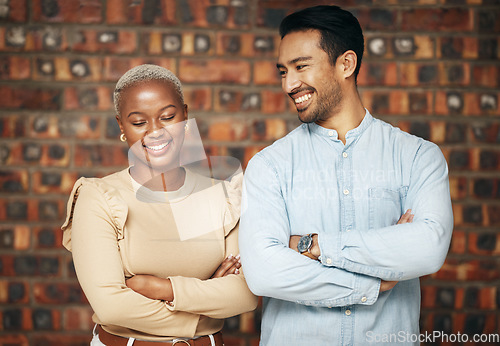 Image of Happy, professional team and partnership, collaboration with smile and arms crossed with friends against brick wall. Work together, employees and diversity, black woman and man, teamwork and trust