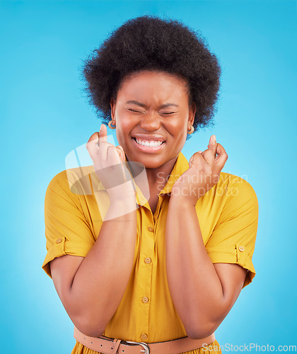 Image of Black woman, fingers crossed and hope in studio, blue background and hopeful face. Female model, wish and hands in lucky bonus, promotion and winning giveaway competition, emoji sign or lottery prize