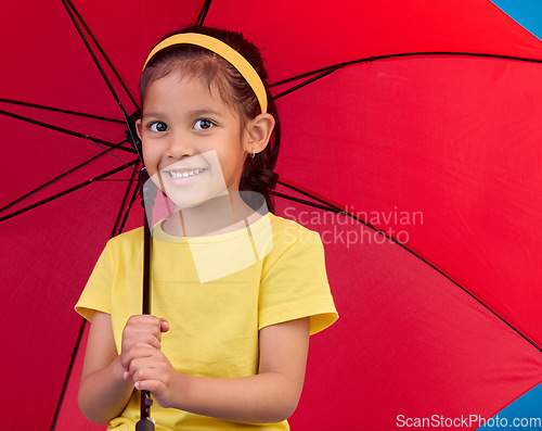 Image of Winter, happy and portrait of a child with an umbrella, open and red while isolated in a studio. Smile, safety and a young girl protecting from the rain, bad weather and the cold for insurance