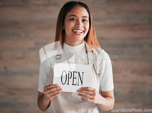 Image of Coffee shop, portrait and woman holding an open sign in studio on a blurred background for hospitality. Cafe, startup and small business with a female entrepreneur indoor to display advertising