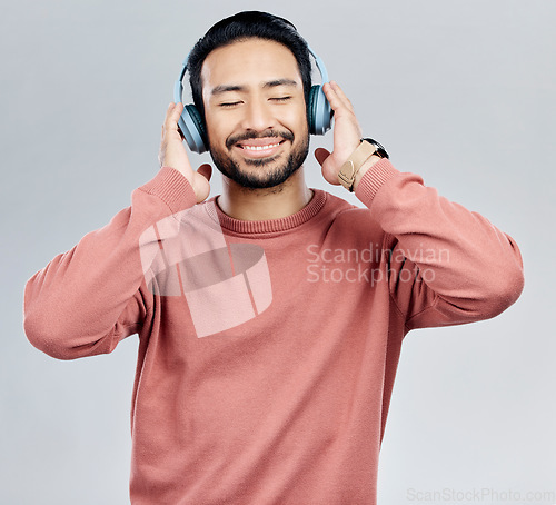 Image of Listen, happy and Asian man with headphones, streaming music and sounds against a white studio background. Japan, male and guy with headset, listening to radio and podcast for motivation and wellness