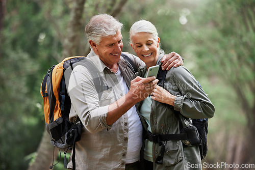 Image of Phone, video call and elderly couple hiking in a forest, happy and smile while bonding on adventure. Active seniors, online and maps for man and woman backpacking in nature while checking location