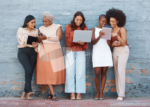 Image of Happy, talking and women on a brick wall with tech for communication, social network and advice. Team, diversity and group of female employees speaking while using technology in the city for work