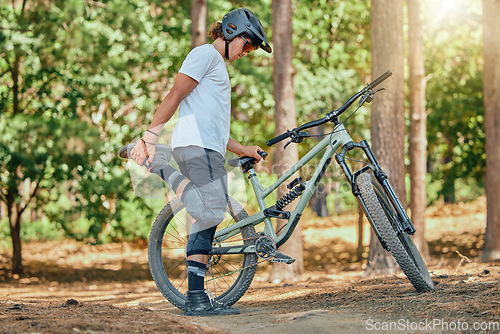 Image of Bike, fitness and man in forest, stretching and workout for balance, cardio and energy for wellness. Male biker, guy and athlete stretch legs, nature and outdoor for exercise, cycling and warm up