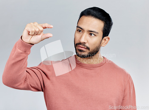 Image of Little, small sign and hand of man in studio on white background to measure size, scale and height. White background, mockup space and serious male with gesture for review, feedback and tiny symbol