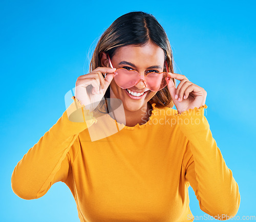 Image of Fashion portrait, heart sunglasses and woman smile with casual spring clothes, designer brand glasses or outfit style. Gen z aesthetic, trendy face and young female model on blue background studio