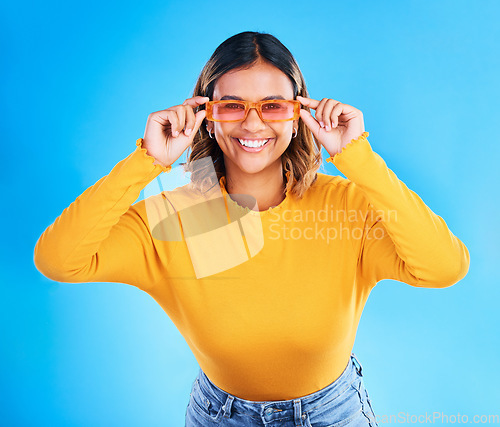 Image of Fashion glasses, happy portrait and woman face with clothes, luxury designer brand or casual outfit style. Gen z summer aesthetic, trendy studio sunglasses and young female model on blue background