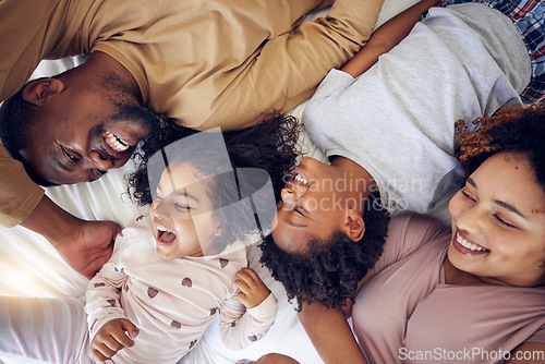 Image of Happy, above and family laughing in bed, smile and bonding while resting in their home. Top view, smile and children waking up with mother and father in a bedroom, playful and having fun