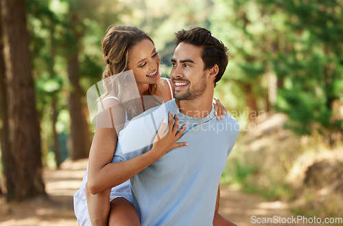 Image of Couple in nature park, piggy back and happy relationship with love and trust, travel and adventure outside. Young people in forest, outdoor and happiness together with smile, commitment and hug