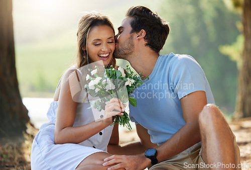 Image of Man kiss woman, picnic with flowers in park with happy couple in nature, love with bonding and relax outdoor. Commitment, trust and relationship, people smile with summer and holiday with travel