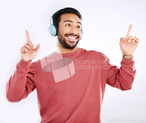 Image of Headphones, smile and male dancing in a studio to music, playlist or album for entertainment. Happiness, dance and Indian man model moving to the radio or streaming a song by a white background.