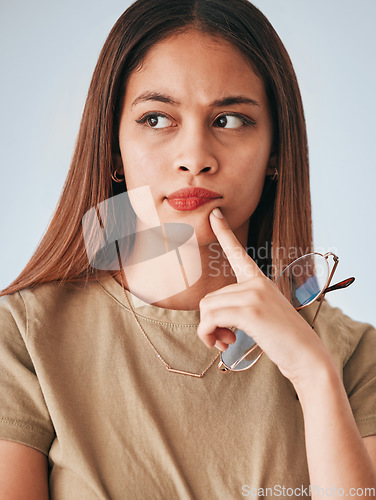 Image of Thinking, woman and glasses of a young female with decision and choice in studio. Isolated planning, solution and contemplation of a person with focus and creative strategy idea feeling thoughtful