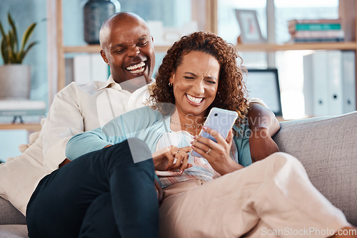 Image of Couple, phone and laughing on sofa in home living room, social media comedy and having fun. Interracial, cellphone and funny black man and mature woman relax browsing online for comic joke or meme.