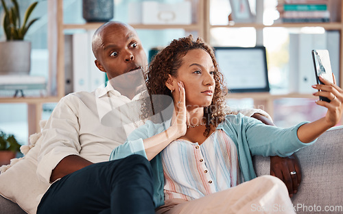 Image of Couple, selfie and funny face on sofa in home living room, bonding or having fun. Interracial, self picture and black man and mature woman relax while taking photo for memory or social media together