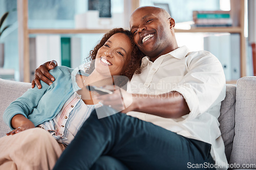 Image of Couple, watching tv and smile on sofa in home living room, bonding and cuddle. Interracial, television and happiness of black man and mature woman relaxing while streaming movie, film or video online