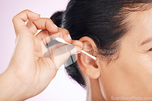 Image of Woman, cotton and cleaning ear in studio in cropped closeup for wellness by pink background. Model hand, self care and clean with hygiene, earwax and natural product for healthy hearing by backdrop