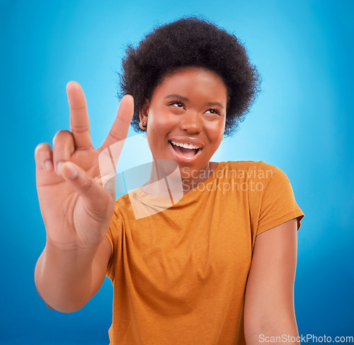 Image of Peace sign closeup, black woman hand and happiness with a young female smile. Isolated, blue background and v hands gesture of a happy African model with a afro and beauty feeling cool and fun