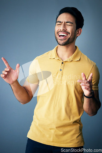 Image of Karaoke, happy and a singing Asian man with a song isolated on a grey background in a studio. Smile, sing and a Japanese singer or artist enjoying, expressing and giving entertainment on a backdrop