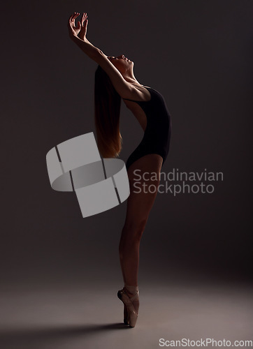 Image of Ballet, woman and artist training, artistic and commitment with girl against a dark studio background. Female performer, lady and ballerina with creativity, happiness and practice for performance