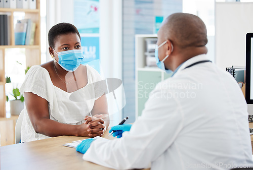 Image of Doctor, patient and consulting with face mask for covid checkup, appointment or diagnosis at hospital. Black man, medical professional talking to woman in consultation or healthcare visit at clinic