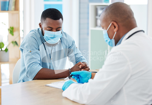 Image of Doctor, covid and black man in consultation for results on clipboard in hospital. Healthcare, face mask and medical professional with paperwork talking with patient for health diagnosis or checkup.