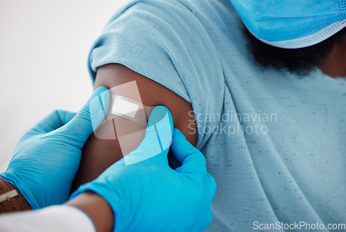 Image of Doctor, hands and plaster on arm after vaccine with patient for safety, prevention and immunity. Healthcare, covid bandage and black man with medical professional after clinic vaccination in hospital