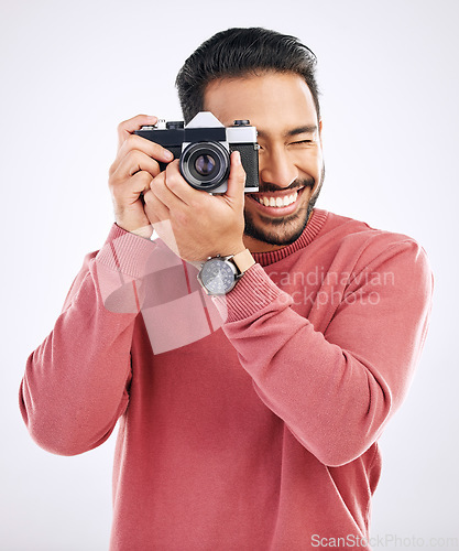 Image of Photography, happy and man with a camera in a studio for creativity or art photoshoot job. Happiness, smile and Indian male photographer taking pictures for paparazzi or the media by white background