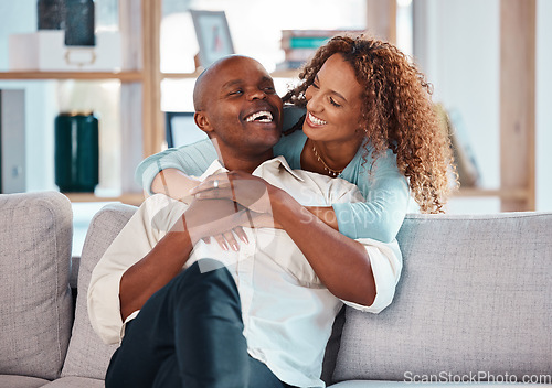 Image of Couple, hug and laughing on sofa in home living room, bonding, relaxing and having fun. Interracial, love and funny black man and woman on couch embrace, happiness and enjoying quality time together